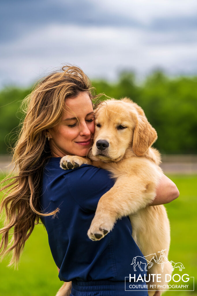 Woman closes her eyes while holding a Golden Retriever puppy.