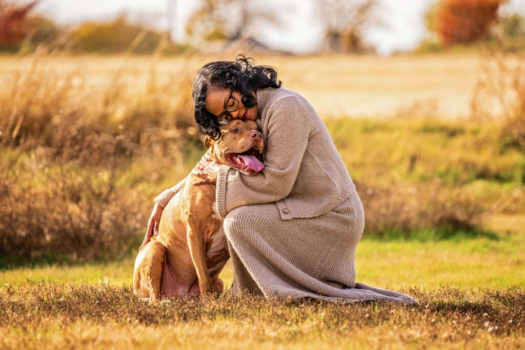 Woman hugging her pit bull in a golden field